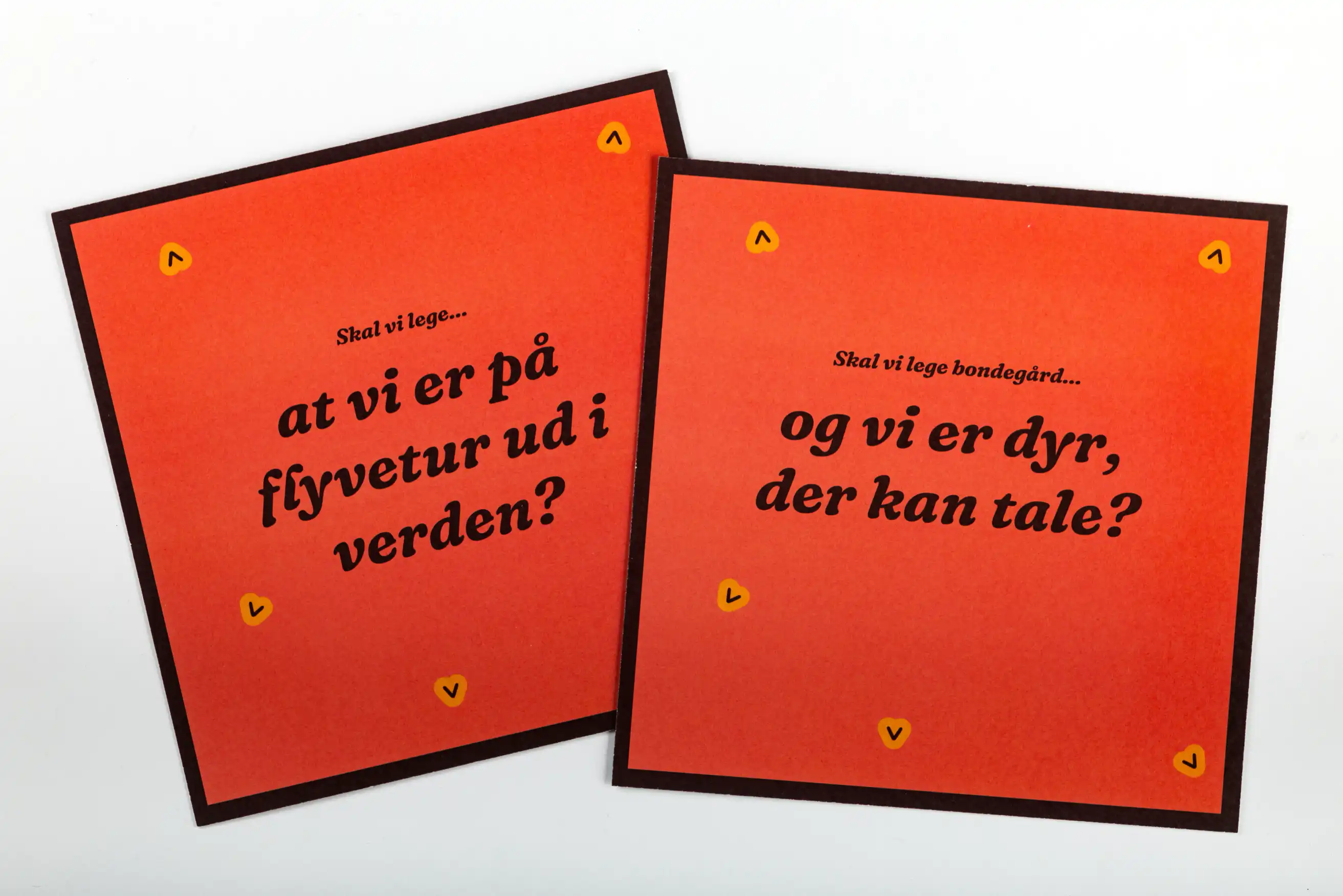 Forsiden af legestarter kortene. To kort overlapper hinanden og har hver deres spørgsmål skrevet på. 