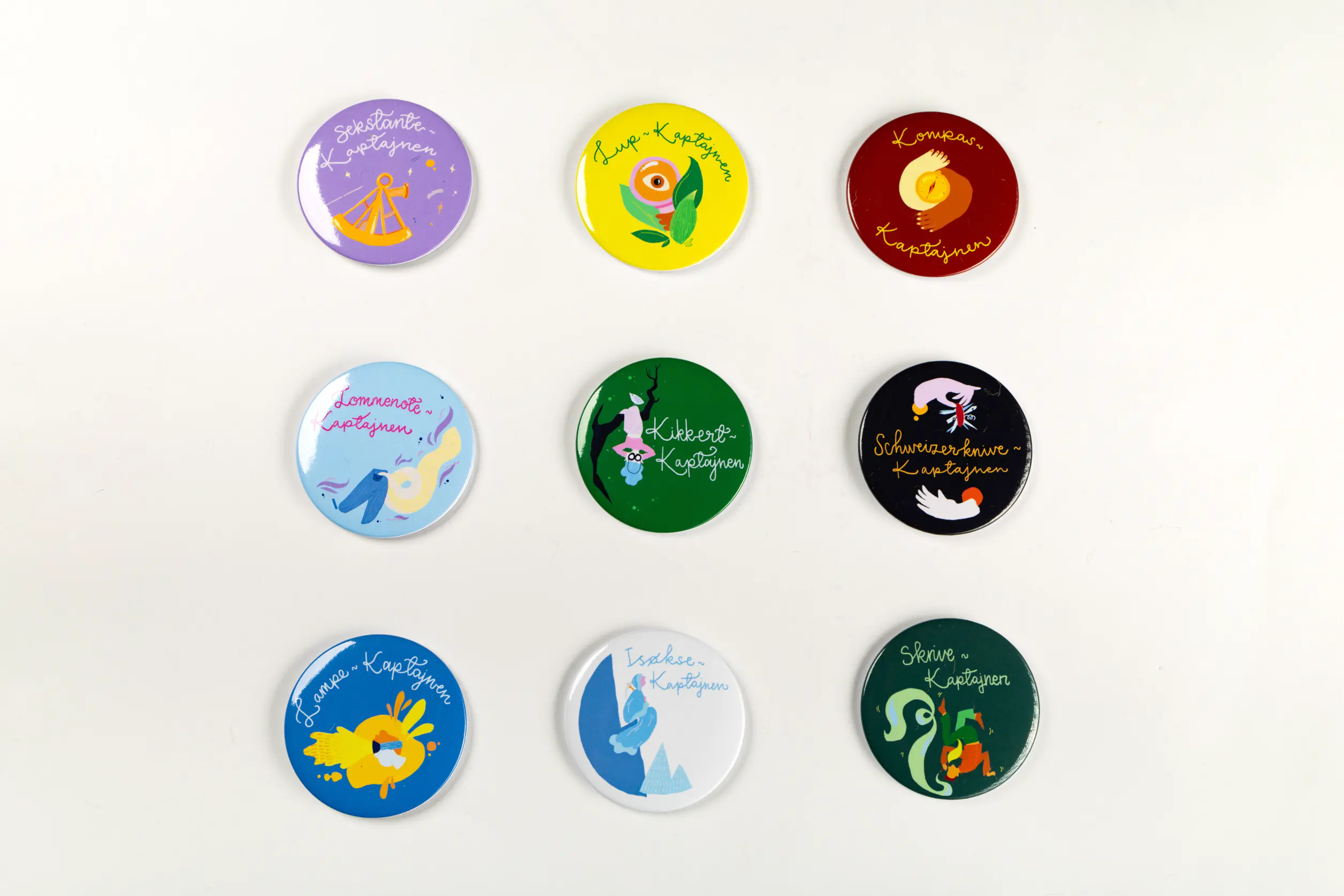 De ni badges til legeløftspillet, med forskellige motiver ligger i en gitteropstilling. 