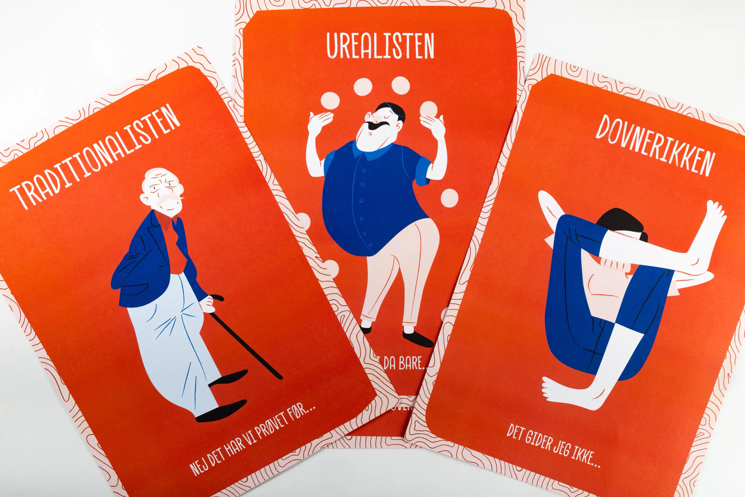 Forsiden af tre af rollekortene. Det første kort viser en illustration af traditionalisten, det næste viser en illustration af urealisten og den sidste viser en illustration af dovnerikken.